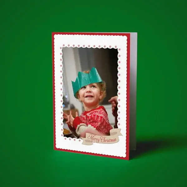Personalised Christmas photo card featuring a child wearing a paper crown, framed with festive red and white border details.